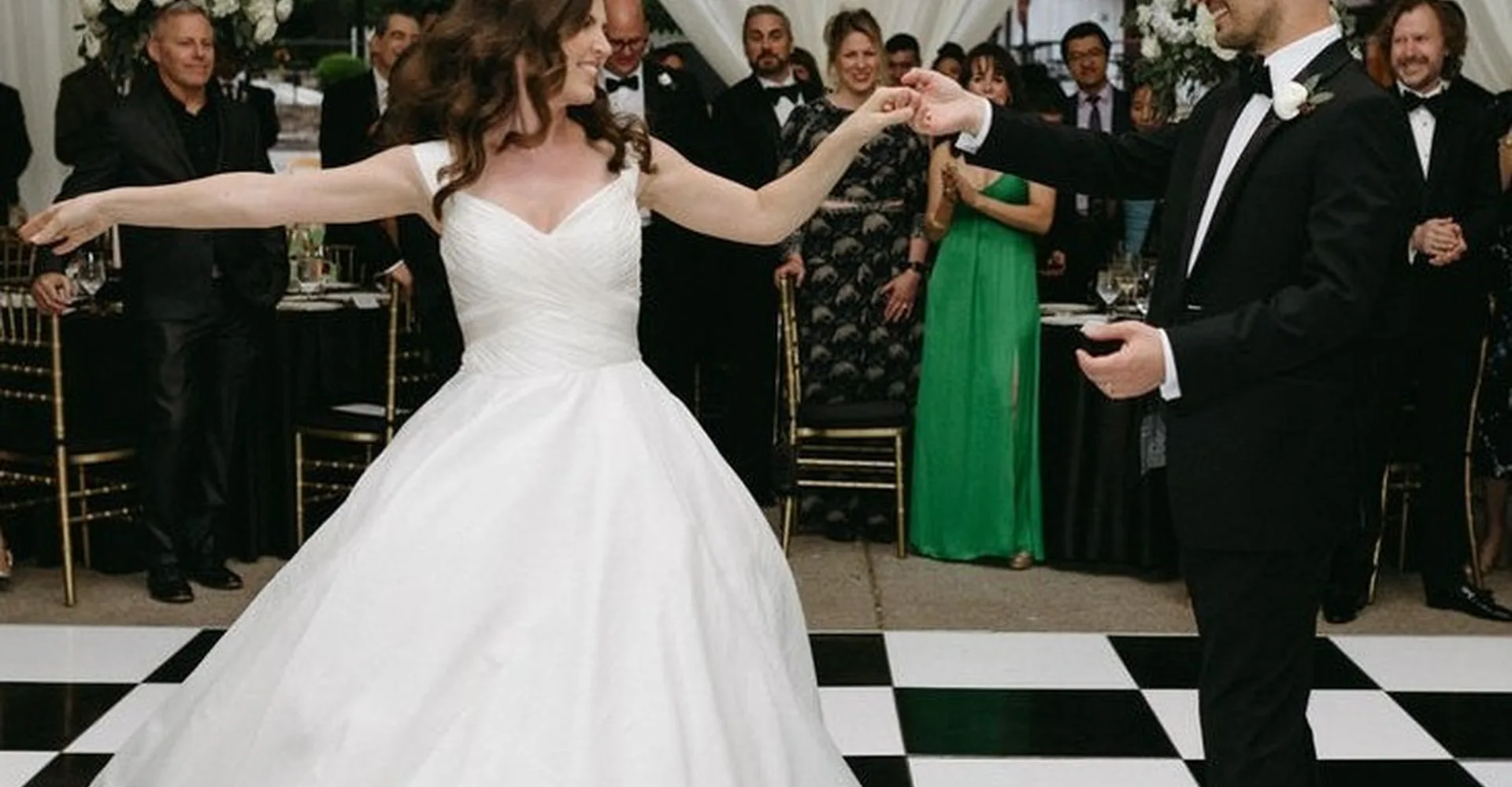 Couple dancing on a checkered floor as guests look on